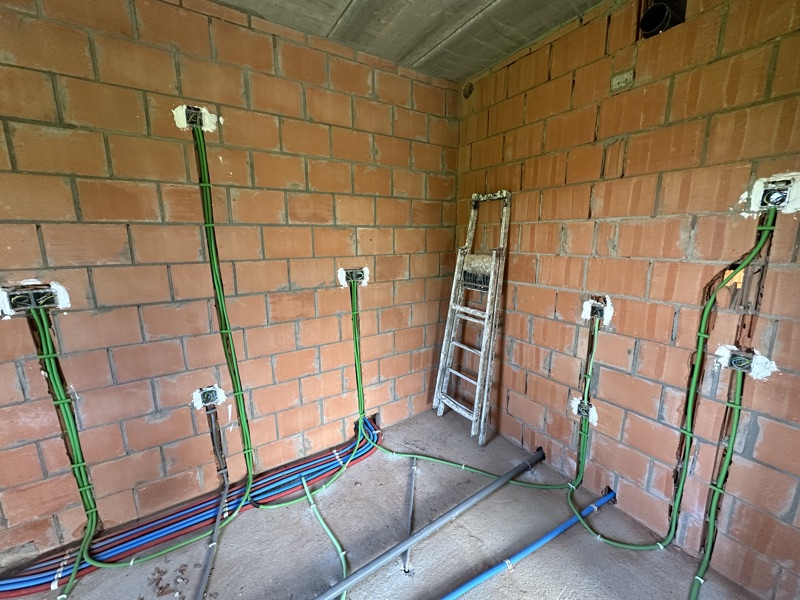 Saignées et gaines préparées sur un mur de briques pour une rénovation électrique complète.